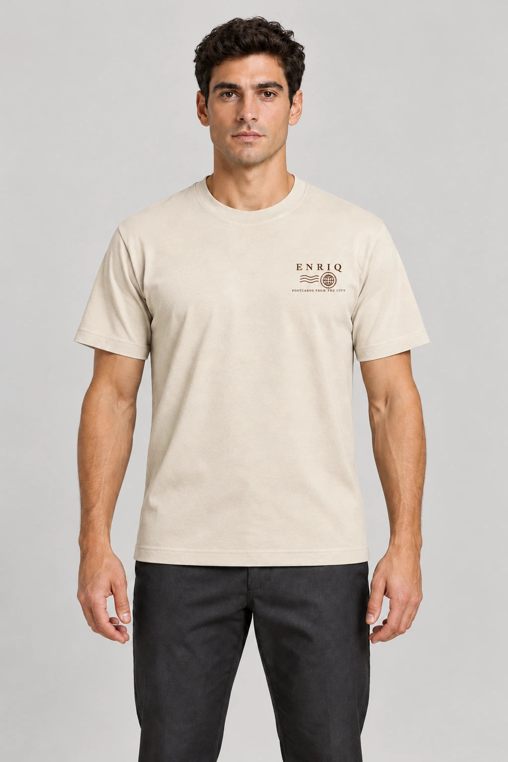 ENRIQ City Stamp Tee Bone – voorkant op model met ENRIQ poststempel-borstlogo (AI-visualisatie)