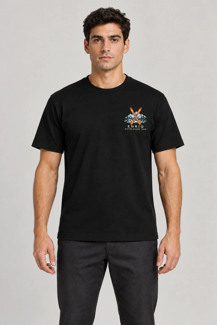 ENRIQ Alpine Grand Tour Tee Black – op model met ski- en bergborstlogo (AI-visualisatie)