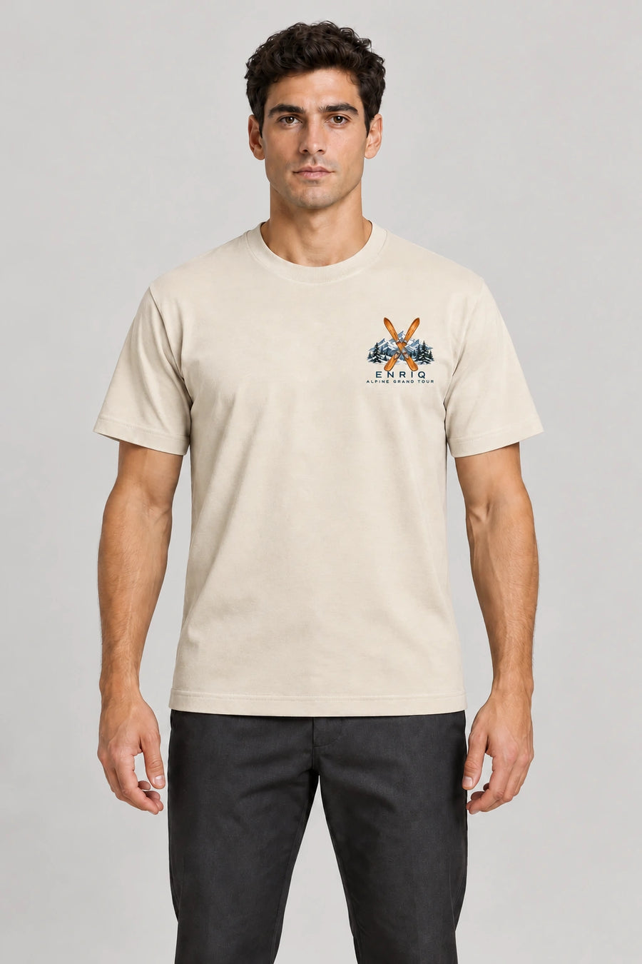 ENRIQ Alpine Grand Tour Tee Bone – op model met ski- en bergborstlogo (AI-visualisatie)