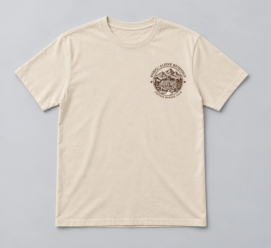 ENRIQ Alpine Residence Tee Bone – flatlay met rond landhuis-borstlogo (AI-visualisatie)