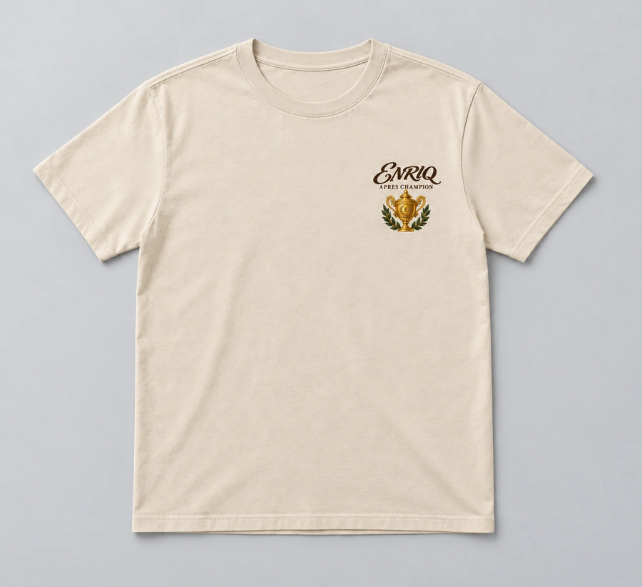 ENRIQ Apres Champion Tee Bone – flatlay met gouden trofee-borstlogo (AI-visualisatie)
