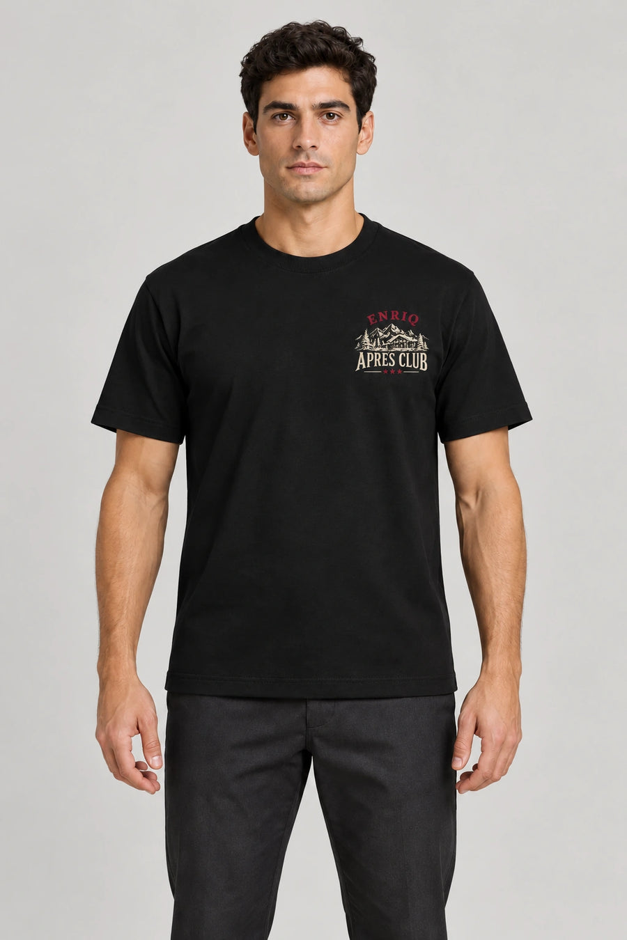 ENRIQ Apres Menu Tee Black – voorkant op model met chalet en APRES CLUB borstlogo (AI-visualisatie)