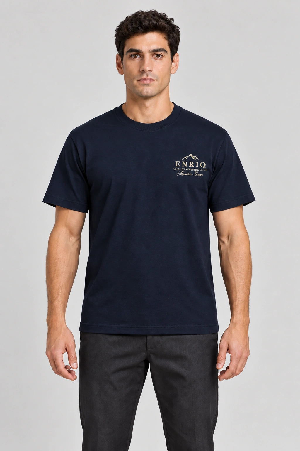 ENRIQ Chalet Owners Tee Navy – voorkant op model met bergtoppen en Chalet Owners Club borstlogo (AI-visualisatie)