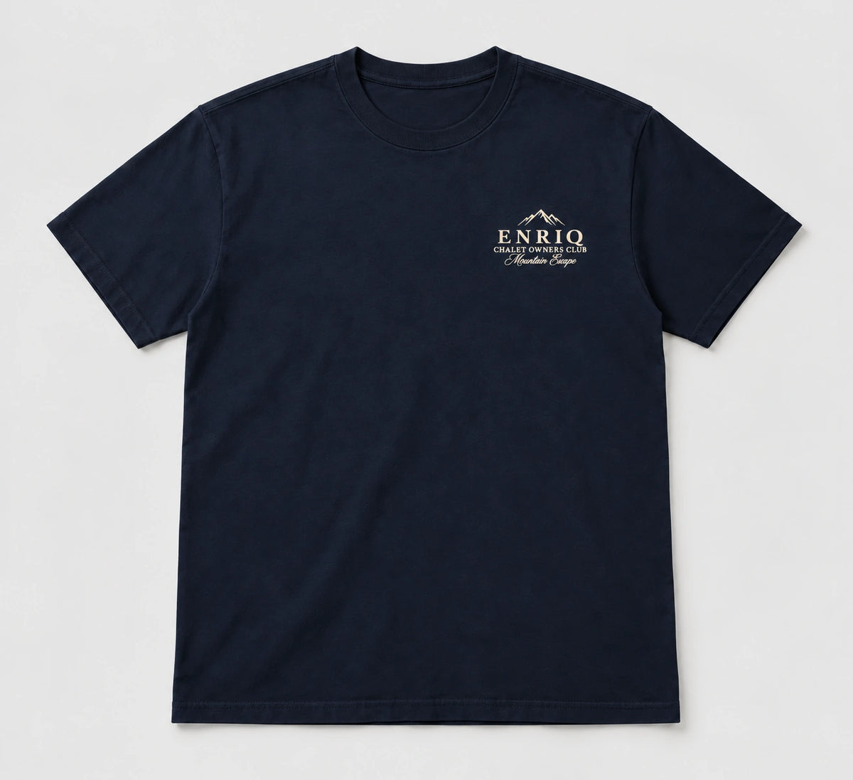 ENRIQ Chalet Owners Tee Navy – flatlay met bergtoppen en Chalet Owners Club borstlogo (AI-visualisatie)