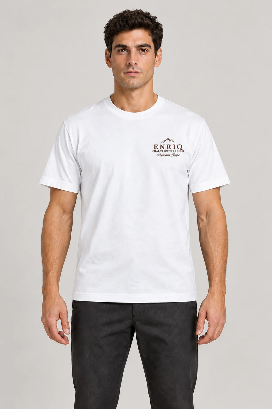 ENRIQ Chalet Owners Tee White – voorkant op model met bergtoppen en Chalet Owners Club borstlogo (AI-visualisatie)