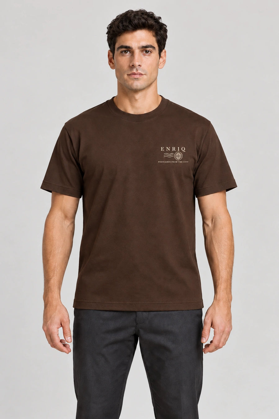 ENRIQ City Stamp Tee Cocoa – voorkant op model met ENRIQ poststempel-borstlogo (AI-visualisatie)