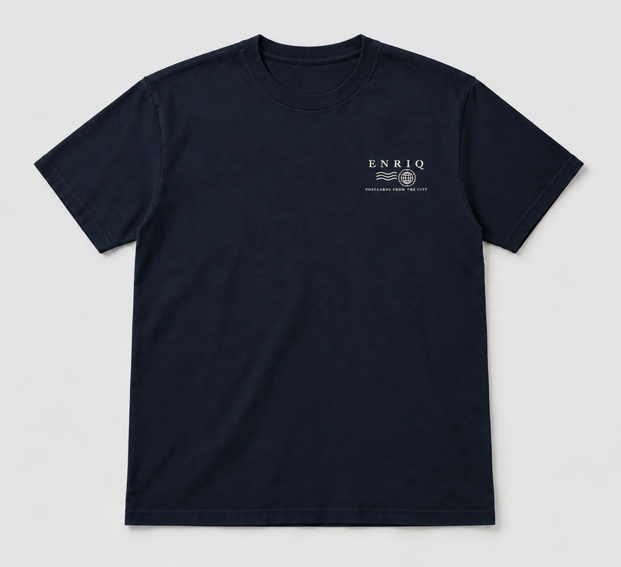 ENRIQ City Stamp Tee Navy – flatlay met ENRIQ poststempel-borstlogo (AI-visualisatie)
